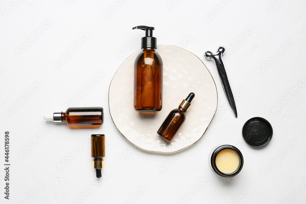 Bottles with cosmetic products and facial massage tool on light background - obrazy, fototapety, plakaty 