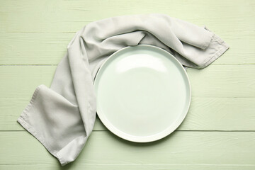 Fabric napkin and plate on color wooden background