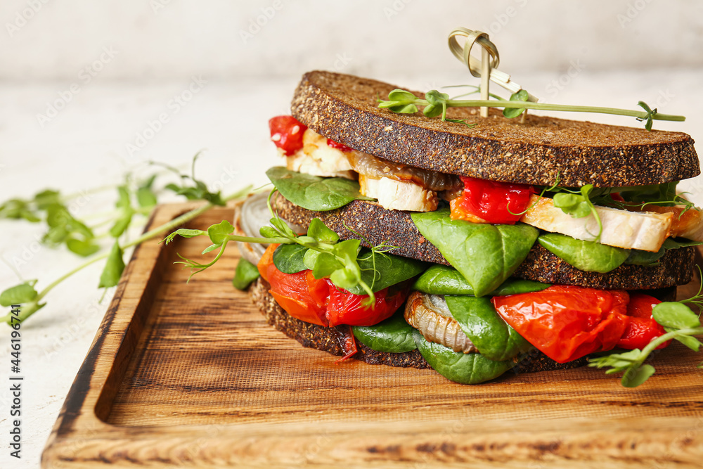 Board with tasty sandwich on light background, closeup