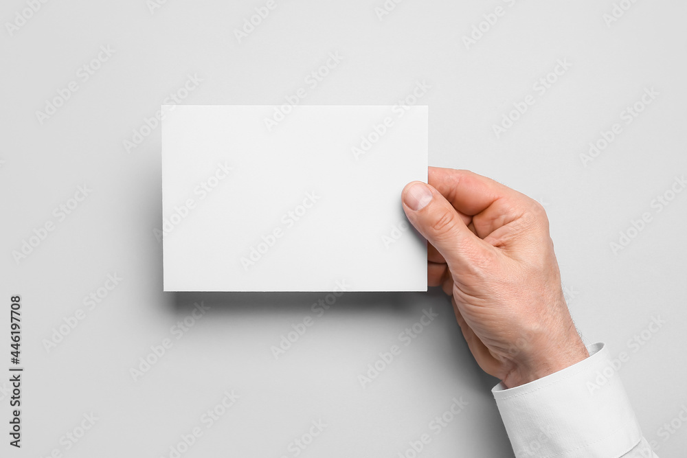 Man holding blank sheet of paper on grey background, closeup
