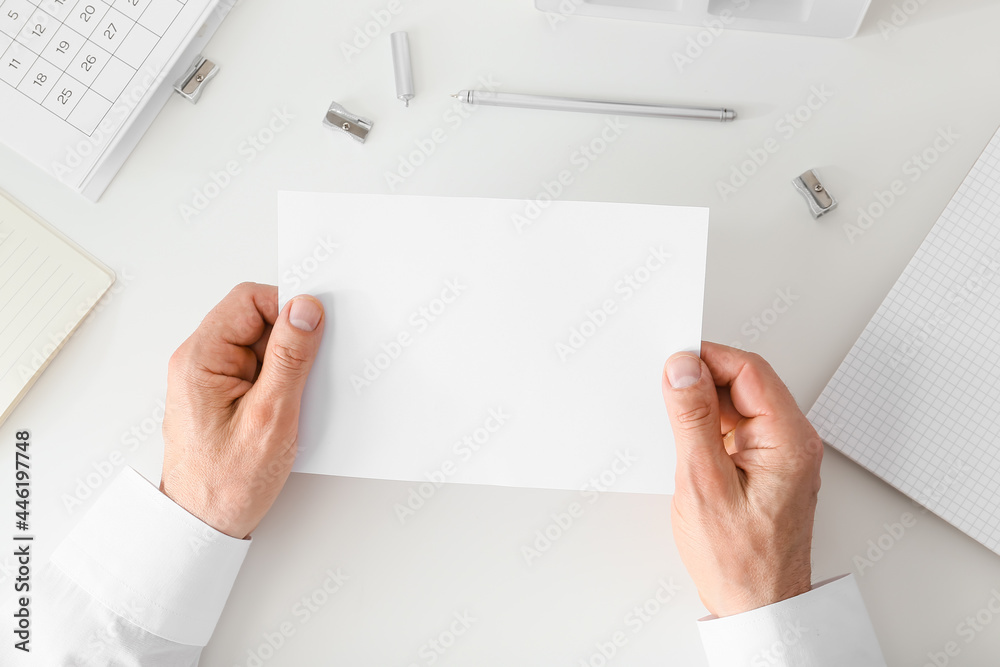 Man holding blank sheet of paper on light background
