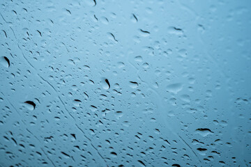 Poster - Raindrops on glass window over grey and blue sky