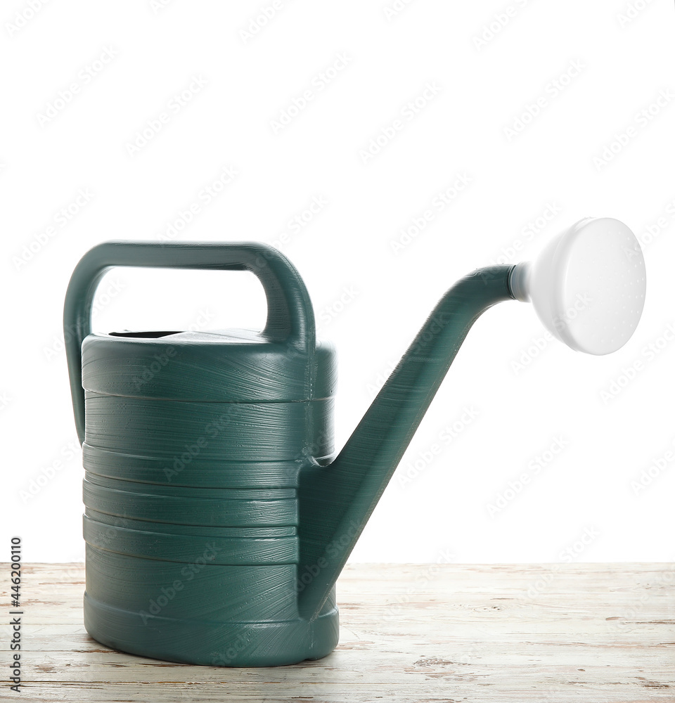 Watering can on wooden table against white background