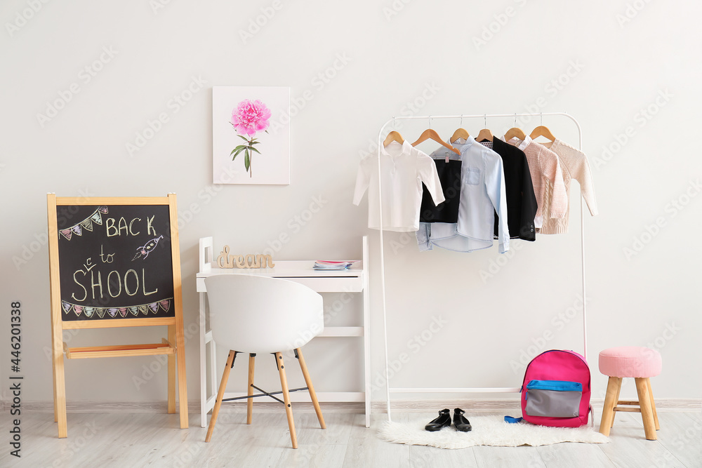 Workplace and rack with school uniform in interior of room