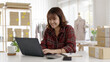 © ChayTee - Young asia people woman female e-commerce parcel work check typing talk to customer on notebook for box shipping online fulfillment sme dropshipping digital dispatch app clothes fashion supply chain.