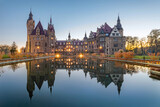 View of Moszna Castle (Moszna Zamek) reflecting in water at dusk, Opole Voivodeship, Poland