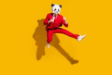 Poster - Photo of kung-fu panda guy jump hold fists kick leg empty space wear mask red tux shoes isolated on yellow color background