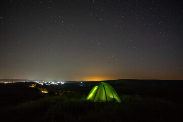 Wall Mural - night landscape tent against the background of the starry sky and city lights