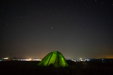 Wall Mural - night landscape tent against the background of the starry sky and city lights