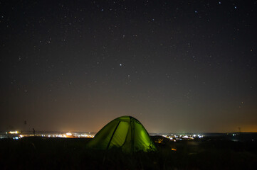 Wall Mural - night landscape tent against the background of the starry sky and city lights