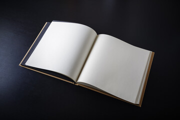 Blank open book on black paper background.