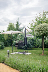 Smoker grill in home backyard, container with coal, smoke coming out of a smokestack, barbecue on green background, family patio, outdoor bbq party on open air