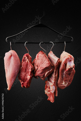 Different cuts of raw meat on hook on hanger