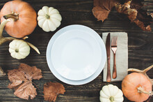 Holiday Place Setting With Plate, Napkin, Antlers And Silverware On A Thanksgiving Day Decorated Table Shot From Flat Lay Or Top View Position. Pumpkins, Antlers And Fallen Leaves. 