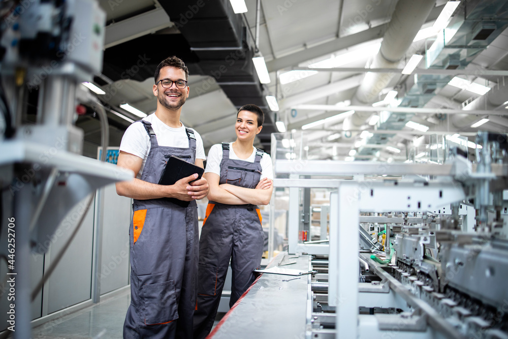 Portrait of production line workers controlling manufacturing process ...