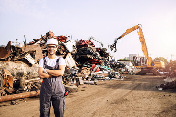 Portrait of junkyard worker standing in scrap metal recycling center.