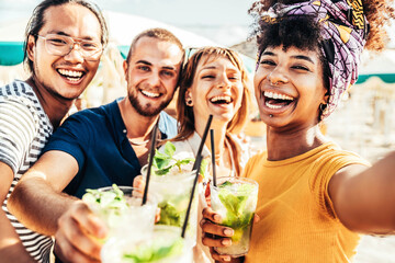 Young people toasting mojito drinks at beach cocktail bar - Happy multiracial friends having fun taking selfie portrait enjoying summer holidays - Youth, beverage and summertime concept