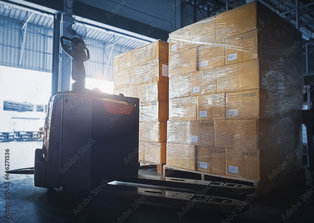 Stacked of Package Boxes with Electric Forklift Pallet Jack at The Storage Warehouse. Shipping Warehouse Logistics. - obrazy, fototapety, plakaty 