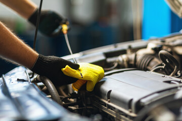 An auto mechanic checks the oil level in a car engine with a special dipstick