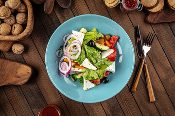 Wall Mural - Plate of greek salad with fresh vegetables on wooden decorated background