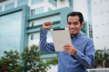 Asian man congratulating on business success, tablet in hand of joyful Asian man
