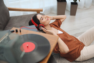 Wall Mural - Woman listening to music with turntable at home