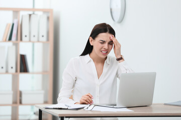 Wall Mural - Woman suffering from migraine at workplace in office