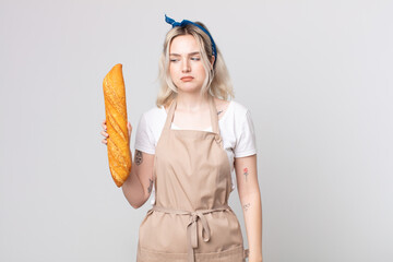 Wall Mural - young pretty albino woman feeling sad, upset or angry and looking to the side with a bread baguette