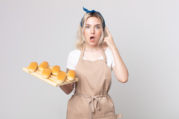 Wall Mural - young pretty albino woman looking surprised, realizing a new thought, idea or concept with a bread buns tray