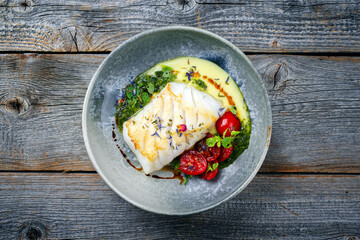 Modern style traditional fried skrei cod fish filet with mashed potato cream and coriander lime relish served as top view on Nordic design plate with copy space