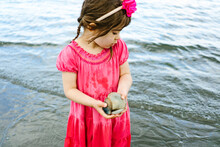 View From Above Of A Young Girl With A Handful Of Sea Shells