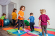 Children running and jumping around multicolor hoops on a floor