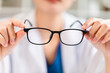 © sirichai - Close-up view of a female doctor holding and showing glasses lens, optics shop.