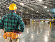 © Andy Dean - Male Contractor Wearing Hard Hat Standing in Empty Industrial Warehouse.