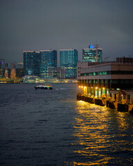 boat leaving a dock in a major port city at night