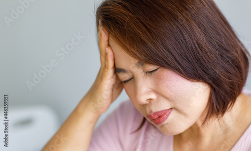 Middle age senior Asian woman feeling pain from sudden headache and brain stroke attack and hold her head with a stressed face. Concept of brain and head problem