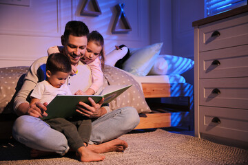 Father reading bedtime story to his children at home