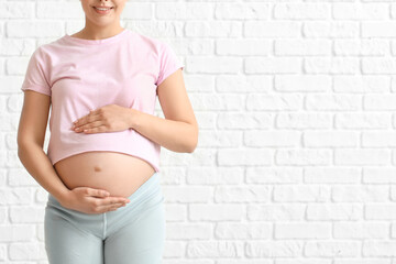 Poster - Young pregnant woman on brick background