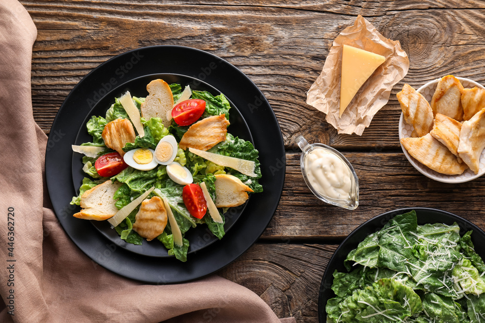 Plate with tasty Caesar salad and sauce on wooden background