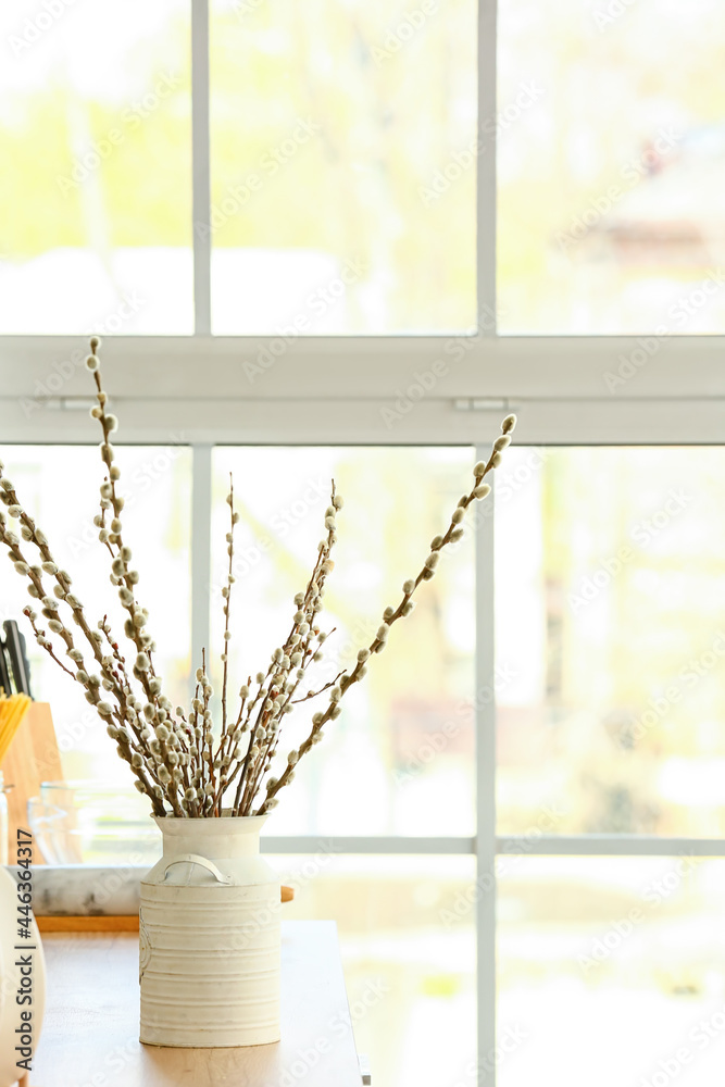 Vase with willow branches on table in kitchen