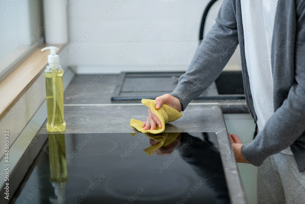 Close up picture of a man cleaning the surface of the table in the kitchen - obrazy, fototapety, plakaty 