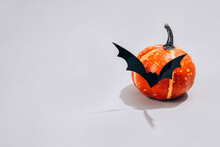 Minimal Halloween Scary Concept - Decorative Orange Pumpkin With Bat Shape Mustache On Light Gray Background With Copy Space. Halloween Decorations Or Party Invitation Concept. Selective Focus