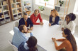 © Studio Romantic - Team of happy business people discussing funny positive stuff in group meeting. High angle shot of diverse corporate company employees and coworkers sitting together around office table and talking