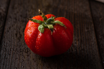 Red tomato on a board  on dark background. Tomato with droplets of water.