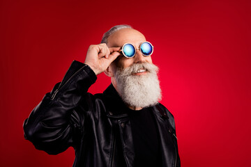 Sticker - Photo of bearded dreamer old man look empty space wear sunglass leather jacket isolated on red color background