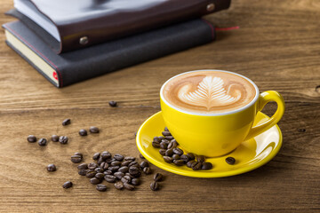 Latte coffee latte art in yellow coffee cup with plate decorated by coffee beans