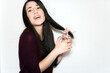 © AliciaFdez - Beautiful brunette woman with a smile cutting her long hair with scissors on a white background. Happy girl