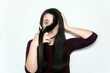 © AliciaFdez - Beautiful brunette woman with a surprised face cutting her long hair with scissors on a white background. Shocked girl
