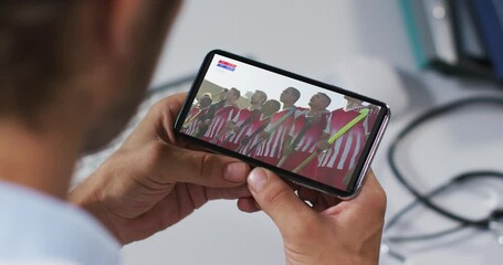 Wall Mural - Composite of male doctor watching hockey match on smartphone