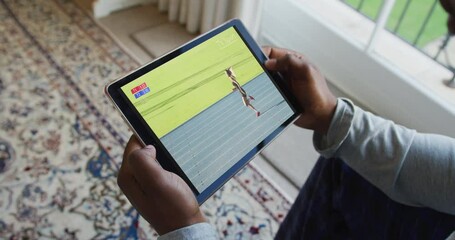 Canvas Print - Composite of man sitting at home, watching athletics running event on tablet